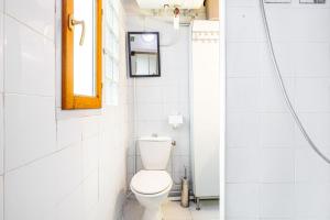 een witte badkamer met een toilet en een raam bij GuestReady - Stylish Hideaway near Bercy Parc in Parijs