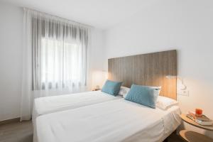 ein Schlafzimmer mit einem großen weißen Bett mit blauen Kissen in der Unterkunft Apartamento Coquette a 50 metros de la playa in Platja  d'Aro