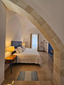 a bedroom with a large bed and an archway at Antica Masseria Torre Mozza in Torre Santa Susanna