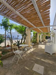 a patio with a table and chairs under a pergola at Antica Masseria Torre Mozza in Torre Santa Susanna