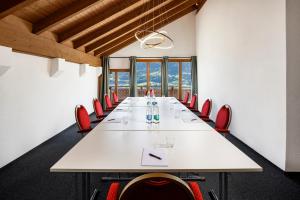 une salle de conférence avec une grande table blanche et des chaises rouges dans l'établissement Hotel und Naturhaus Bellevue, à Seelisberg