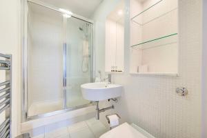 a white bathroom with a sink and a shower at GuestReady - Uma escapadela encantadora em Highbury in London