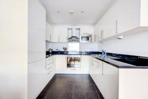 a white kitchen with white cabinets and black counter tops at GuestReady - Uma escapadela encantadora em Highbury in London