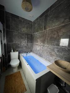 Un baño con bañera azul y un inodoro. en Maison JO 2024, en Villepinte 3 fotos más