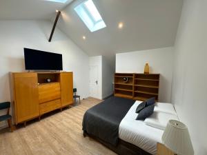 ein Schlafzimmer mit einem Bett und einem TV auf einer Kommode in der Unterkunft La Grange de Witry in Witry-lès-Reims