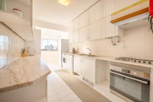 cocina grande con armarios blancos y fregadero en GuestReady - Charming stay with a terrace, en Carcavelos