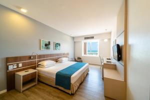 um quarto de hotel com uma cama e uma televisão em Oasis Imperial & Fortaleza em Fortaleza