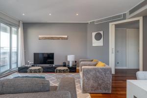 GuestReady - Apartamento com vista para o mar e terraço في برشلونة: غرفة معيشة مع كرسيين وتلفزيون