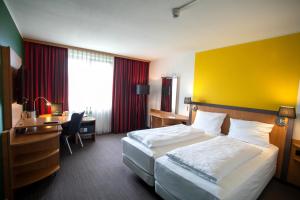 um quarto de hotel com uma cama e uma secretária em SleepBEEONE AIRPORTHOTEL FRANKFURT MÖRFELDEN em Mörfelden-Walldorf