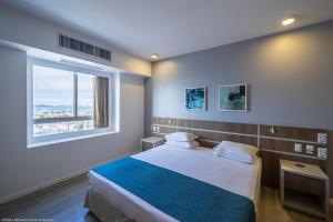um quarto com uma cama e uma janela grande em Oasis Imperial & Fortaleza em Fortaleza