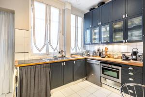 eine Küche mit dunkelblauen Schränken und einem Waschbecken in der Unterkunft GuestReady - Homely Getaway in Neuilly in Neuilly-sur-Seine