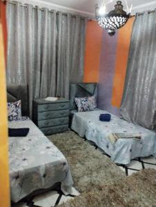 1 Schlafzimmer mit 2 Einzelbetten und einem Kronleuchter in der Unterkunft Villas khadija in Marrakesch