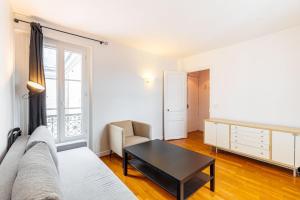 een woonkamer met een bank en een tafel bij GuestReady - Parisian Perch with Eiffel Tower View in Parijs
