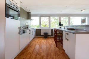 een keuken met witte kasten en een houten vloer bij Hello Zeeland - Essenhoeve 2 Rosa Rugosa in Cadzand