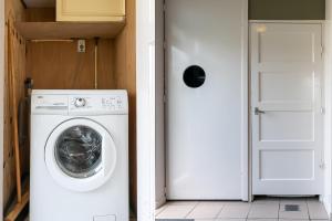 een witte wasmachine in een kamer met een deur bij Hello Zeeland - Essenhoeve 2 Rosa Rugosa in Cadzand