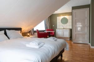 1 dormitorio con 1 cama blanca grande y toallas. en Hello Zeeland - Essenhoeve 2 Rosa Rugosa, en Cadzand