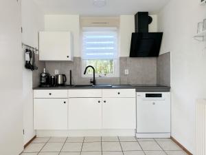 a kitchen with white cabinets and a sink and a window at Bungalow 36 op Recreatiepark De Wielen in Sint Maarten +25 photos