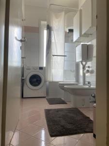een witte badkamer met een wasmachine en een wastafel bij Cadolini Apartment in Milaan