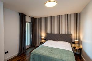 a bedroom with a bed and two tables with lamps at Apartments Stone house in Tribunj