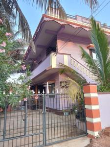 HonāvarVian Homestay的粉红色的房子,前面有栅栏