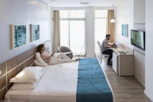 uma mulher sentada numa cama num quarto de hospital em Oasis Imperial & Fortaleza em Fortaleza