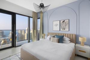 um quarto branco com uma cama grande e janelas grandes em GuestReady - Vida High-Floor Elegance em Dubai