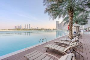 a row of chaise lounge chairs next to a swimming pool at GuestReady - Viver com glamour em Palm Jumeirah in Dubai