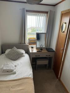 1 dormitorio con 1 cama y escritorio con ordenador en Impala Guest House en Wick