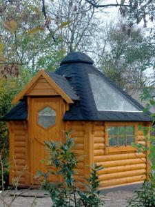 a large wooden cabin with a black roof at Sterrenzicht BB Weidszicht in Doezum