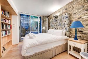 a bedroom with a brick wall and a bed with a blue lamp at GuestReady - Lower Ground Classic near The Oval in London