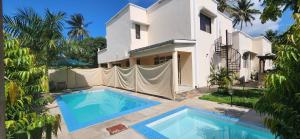 a villa with a swimming pool in front of a house at Villa Salaam in Diani Beach