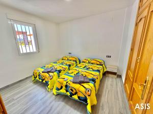Un dormitorio con tres camas con mantas amarillas y una ventana. en Apartamaento Asis A, en Albuñán