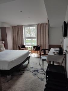 リュネヴィルにあるLogis Hôtel Les Pagesのベッドルーム1室(ベッド1台、テーブル、椅子付)
