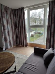 a living room with a couch and a large window at Logis Hôtel Les Pages in Lunéville