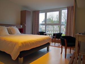 a bedroom with a bed and a large window at Logis Hôtel Les Pages in Lunéville