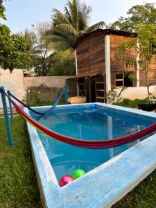 a swimming pool with a hammock in front of a house at Cabana Bacalar in Bacalar