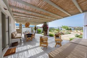 Villa Paralía - Best seaside في Agia Irini Paros: فناء به بروجولا خشبي وطاولة وكراسي