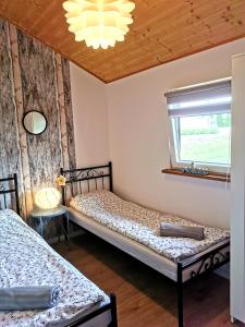 Duas camas num quarto com uma janela e um lustre em Strumyk Marzeń em Mikolajki