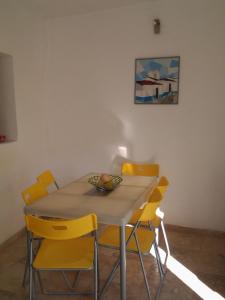 a dining room table with yellow chairs around it at Typical small house near Lisbon in Oeiras
