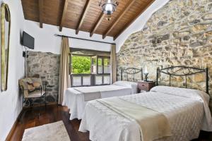 um quarto com 2 camas e uma parede de pedra em Casa De Aldea La Venta Los Probes em Llanes