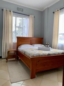 a bedroom with a bed with a wooden frame and a window at Peakline Apartments in Arusha +49 photos