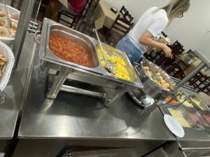 a person preparing food in a restaurant kitchen at Garden Hotel in Aparecida +82 photos