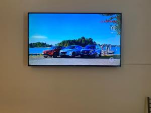 a flat screen tv hanging on a wall with four cars at villa martina suite apartament in Lacco Ameno +59 photos
