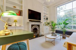 a living room with a fireplace and a tv at Bright Camberwell Georgian Apartment in London