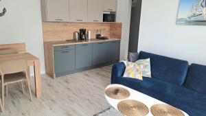 a living room with a blue couch and a kitchen at Aurora Apartament Gardenia in Międzywodzie