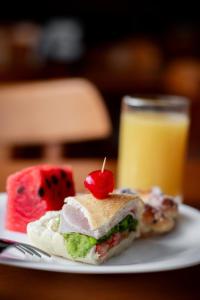 un sándwich y una cereza en un plato con una bebida en Augusta Hotel en João Neiva