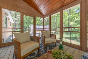 a screened porch with two chairs and a table at Nature lovers delight, private hot tub and a short walk to Lake MI in Fennville