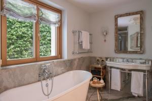 a bathroom with a tub and a sink and a mirror at Passalacqua in Moltrasio