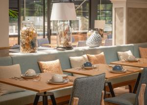 un restaurante con mesas y sillas de madera y ventanas en Hôtel Arcanse by Inwood Hotels en Arcachon
