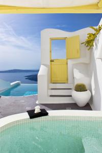 a villa with a yellow door and a swimming pool at Dreams Luxury Suites in Imerovigli